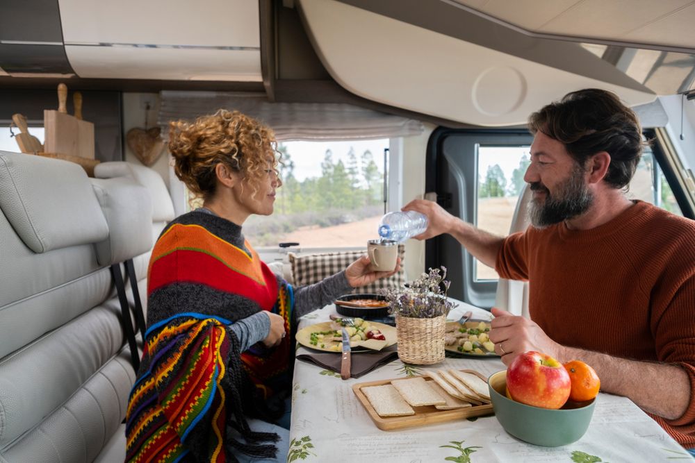 An adult couple eating a home-cooked meal in their RV.