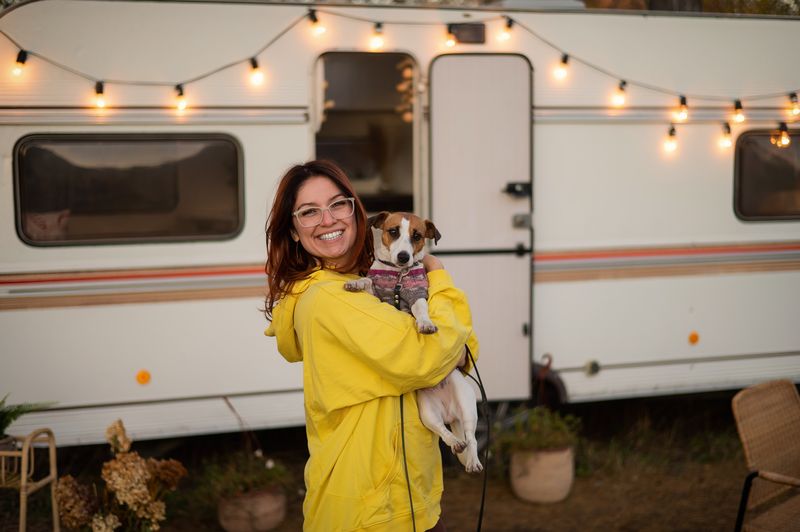 Woman holding a small dog outside her RV while RV camping with dogs.