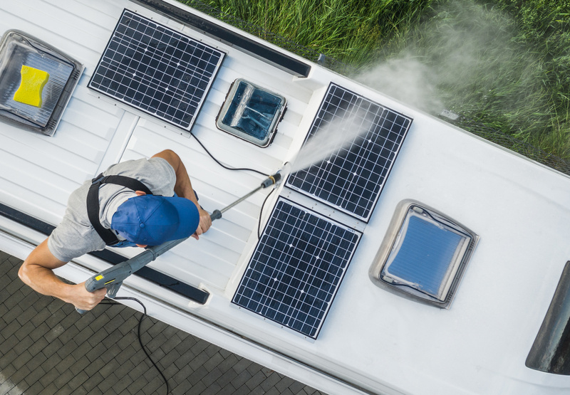 Man washes the solar panels on the roof of his RV.