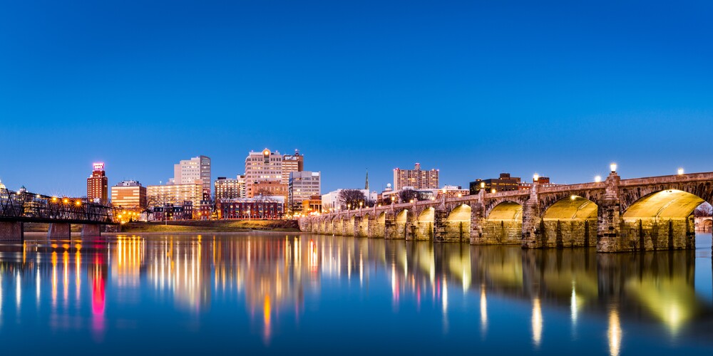 Harrisburg, Pennsylvania skyline with the historic Market Street Bridge reflected on the Susquehanna River at dusk.