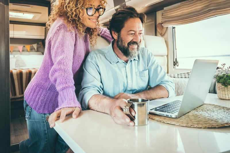 Couple in their RV look at a laptop together to determine if financing a new RV is right for them. 